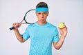 Young hispanic boy playing tennis holding racket and ball depressed and worry for distress, crying angry and afraid Royalty Free Stock Photo