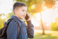 Young Hispanic Boy Walking Outdoors With Backpack Talking on Cell Phone