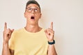 Young hispanic boy wearing casual clothes and glasses amazed and surprised looking up and pointing with fingers and raised arms Royalty Free Stock Photo