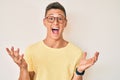 Young hispanic boy wearing casual clothes and glasses celebrating victory with happy smile and winner expression with raised hands Royalty Free Stock Photo