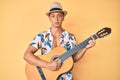 Young hispanic boy wearing summer style playing classical guitar relaxed with serious expression on face Royalty Free Stock Photo