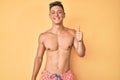 Young hispanic boy wearing swimwear shirtless smiling happy and positive, thumb up doing excellent and approval sign Royalty Free Stock Photo