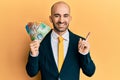 Young hispanic business man holding canadian dollars smiling happy pointing with hand and finger to the side Royalty Free Stock Photo