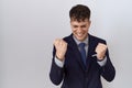 Young hispanic business man wearing suit and tie very happy and excited doing winner gesture with arms raised, smiling and Royalty Free Stock Photo