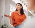 Young hispanic business woman from below speaking to colleagues during a meeting in an office boardroom. Woman asking a Royalty Free Stock Photo