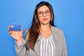 Young hispanic business woman holding credit card over blue isolated background with a confident expression on smart face thinking Royalty Free Stock Photo