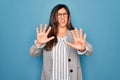 Young hispanic business woman wearing glasses standing over blue isolated background afraid and terrified with fear expression Royalty Free Stock Photo