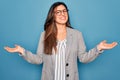 Young hispanic business woman wearing glasses standing over blue isolated background smiling showing both hands open palms, Royalty Free Stock Photo