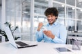 Young hispanic businessman sitting in the office at the desk and using the phone. He looks at the screen, dials Royalty Free Stock Photo