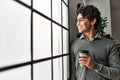 Young hispanic businessman smiling happy drinking coffee at the office Royalty Free Stock Photo