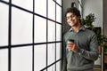 Young hispanic businessman smiling happy drinking coffee at the office Royalty Free Stock Photo