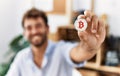 Young hispanic businessman smiling happy holding bitcoin at the office Royalty Free Stock Photo