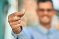 Young hispanic businessman smiling happy holding 1 euro coin at the city Royalty Free Stock Photo