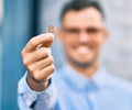 Young hispanic businessman smiling happy holding 1 euro coin at the city Royalty Free Stock Photo