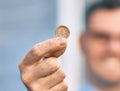 Young hispanic businessman smiling happy holding 1 euro coin at the city Royalty Free Stock Photo