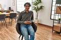 Young hispanic businessman smiling happy sitting on chair at the office Royalty Free Stock Photo