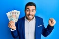 Young hispanic businessman wearing business suit holding czech koruna banknotes screaming proud, celebrating victory and success Royalty Free Stock Photo