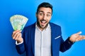 Young hispanic businessman wearing business suit holding russian ruble banknotes celebrating achievement with happy smile and