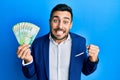 Young hispanic businessman wearing business suit holding russian ruble banknotes screaming proud, celebrating victory and success Royalty Free Stock Photo