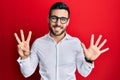 Young hispanic businessman wearing shirt and glasses showing and pointing up with fingers number eight while smiling confident and