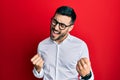 Young hispanic businessman wearing shirt and glasses very happy and excited doing winner gesture with arms raised, smiling and Royalty Free Stock Photo