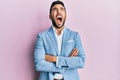 Young hispanic businessman wearing suit with arms crossed gesture angry and mad screaming frustrated and furious, shouting with Royalty Free Stock Photo