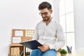 Young hispanic businessman writing on  clipboard sitting on the table at the office Royalty Free Stock Photo