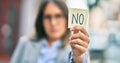 Young hispanic businesswoman with serious expression holding reminder with no message at the city