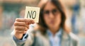 Young hispanic businesswoman with serious expression holding reminder with no message at the city