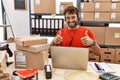 Young hispanic call center agent man working at warehouse approving doing positive gesture with hand, thumbs up smiling and happy Royalty Free Stock Photo