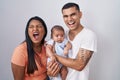 Young hispanic couple with baby standing together over isolated background angry and mad screaming frustrated and furious,