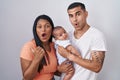 Young hispanic couple with baby standing together over isolated background surprised pointing with hand finger to the side, open Royalty Free Stock Photo