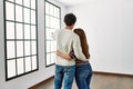 Young hispanic couple on back view hugging and standing at empty new home Royalty Free Stock Photo