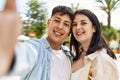 Young hispanic couple of boyfriend and girlfriend together outdoors on a sunny day, smiling in love taking a selfie picture Royalty Free Stock Photo