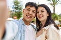 Young hispanic couple of boyfriend and girlfriend together outdoors on a sunny day, smiling in love taking a selfie picture Royalty Free Stock Photo