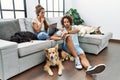 Young hispanic couple with dogs relaxing at home checking the time on wrist watch, relaxed and confident