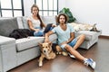 Young hispanic couple with dogs relaxing at home relaxed with serious expression on face