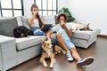 Young hispanic couple with dogs relaxing at home smelling something stinky and disgusting, intolerable smell, holding breath with Royalty Free Stock Photo