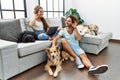 Young hispanic couple with dogs relaxing at home smiling with hand over ear listening an hearing to rumor or gossip