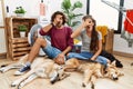 Young hispanic couple doing laundry with dogs peeking in shock covering face and eyes with hand, looking through fingers with