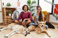 Young hispanic couple doing laundry with dogs relaxed with serious expression on face