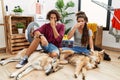 Young hispanic couple doing laundry with dogs smelling something stinky and disgusting, intolerable smell, holding breath with