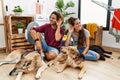 Young hispanic couple doing laundry with dogs smiling with hand over ear listening an hearing to rumor or gossip