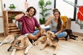 Young hispanic couple doing laundry with dogs smiling doing phone gesture with hand and fingers like talking on the telephone