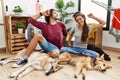 Young hispanic couple doing laundry with dogs stretching back, tired and relaxed, sleepy and yawning for early morning