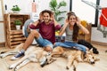 Young hispanic couple doing laundry with dogs trying to hear both hands on ear gesture, curious for gossip