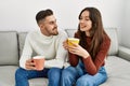 Young hispanic couple drinking coffee sitting on the sofa at home Royalty Free Stock Photo