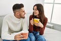 Young hispanic couple drinking coffee sitting on the sofa at home Royalty Free Stock Photo