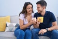 Young hispanic couple drinking coffee sitting on sofa at home Royalty Free Stock Photo