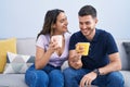 Young hispanic couple drinking coffee sitting on sofa at home Royalty Free Stock Photo